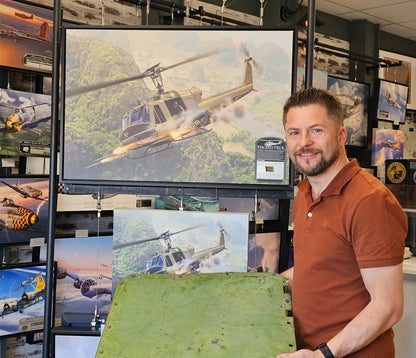 Photo of artist standing next to the Huey print canvas and holding the large relic piece.